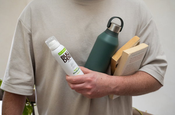 Man holding deodorant bottle, water flask and books